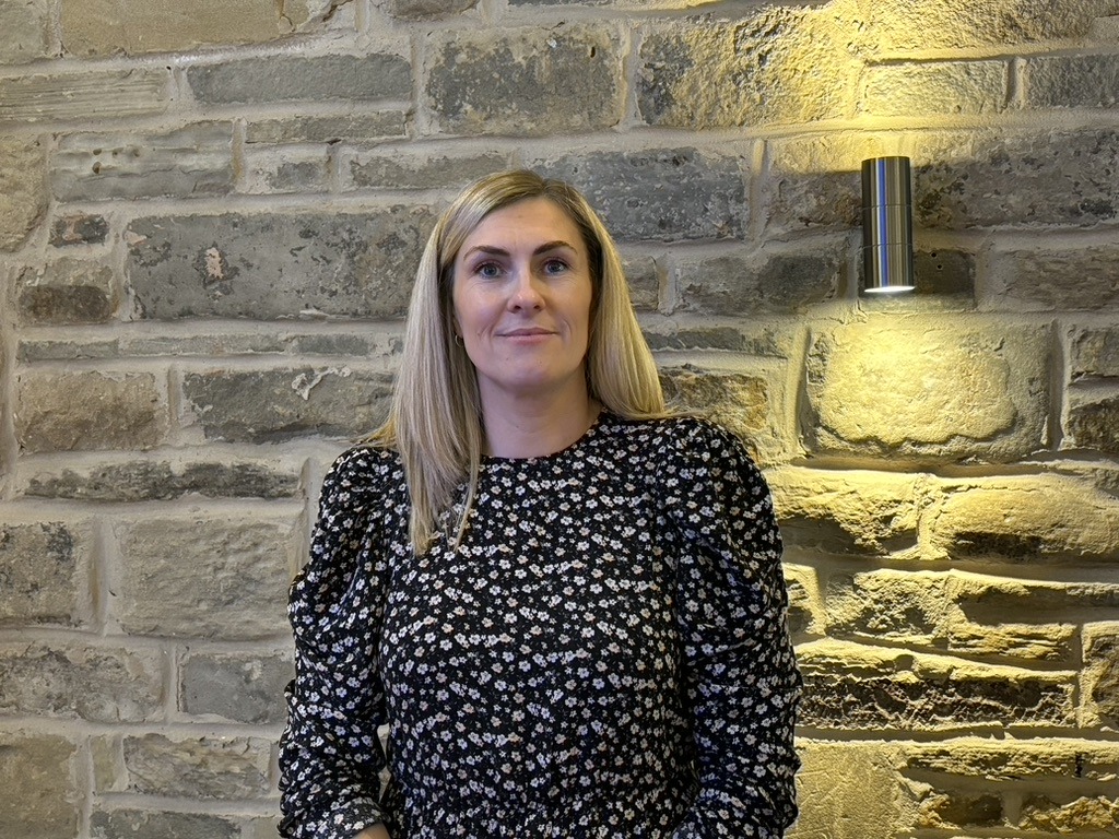 Sarah Gray standing in front of stone wall. Sarah has been named in GreenFleet 100 Most influential for her work driving forward Sustainable Transportation.